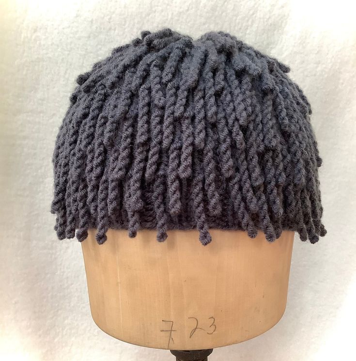 a mannequin head wearing a knitted hat on top of a wooden stand