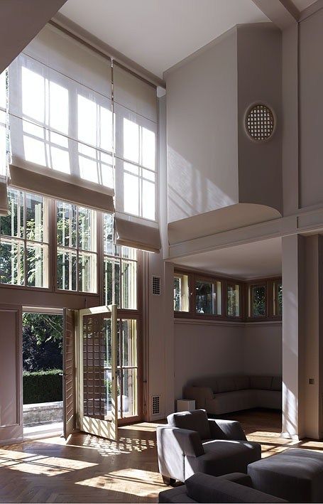 the sun shines through large windows into a living room