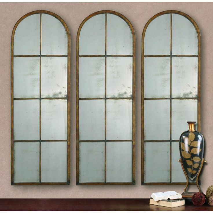 three arched windows with gold trim on each side and two vases next to them