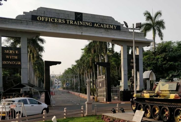 the entrance to officers training academy with tanks and cars parked on the street below it