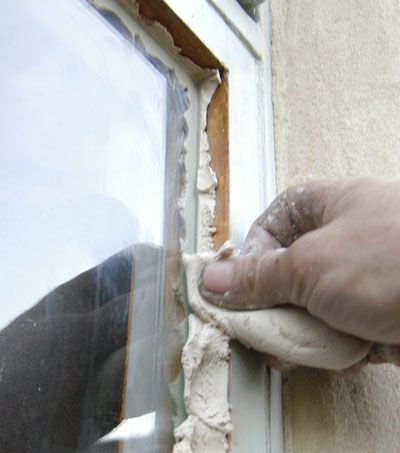 a person is holding something in their hand near a window that has been torn open