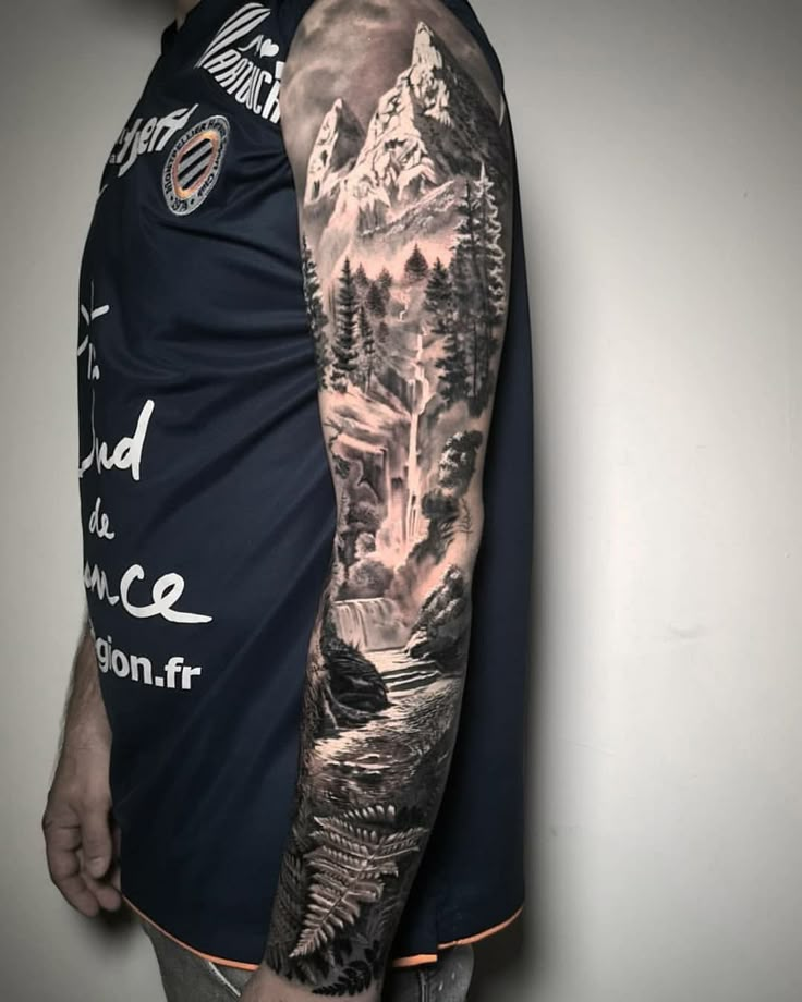 a man with a full sleeve mountain scene tattoo on his left arm and right arm