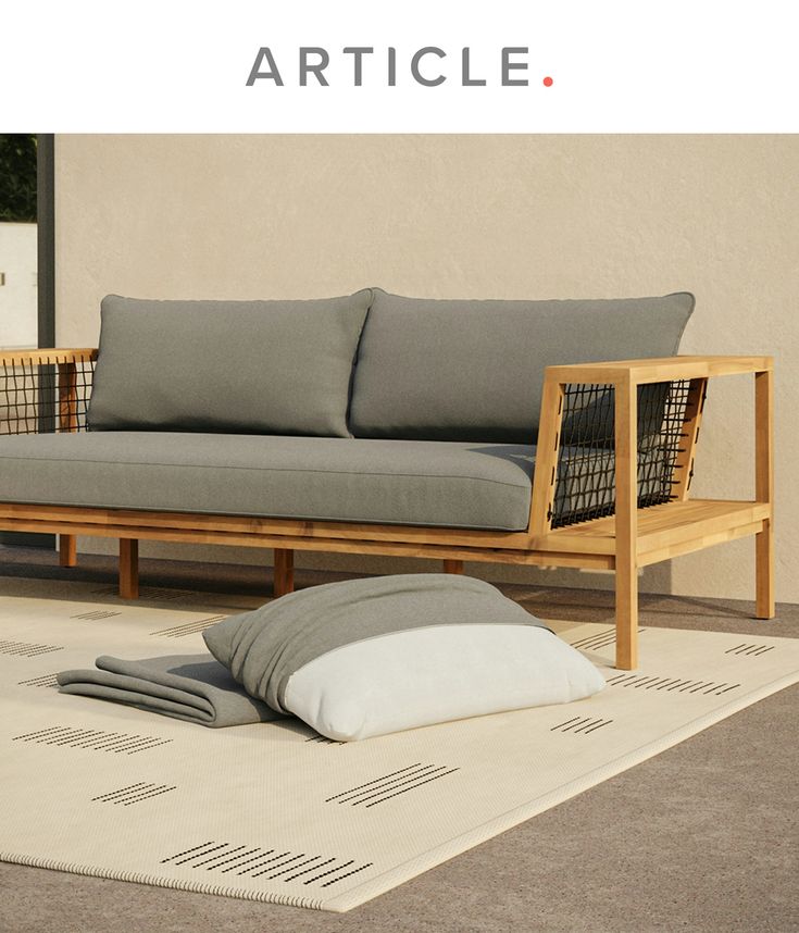 a couch sitting on top of a white rug next to a wooden frame and pillow