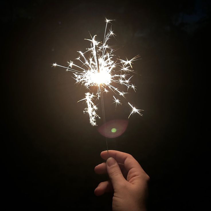 a hand holding a sparkler in the dark