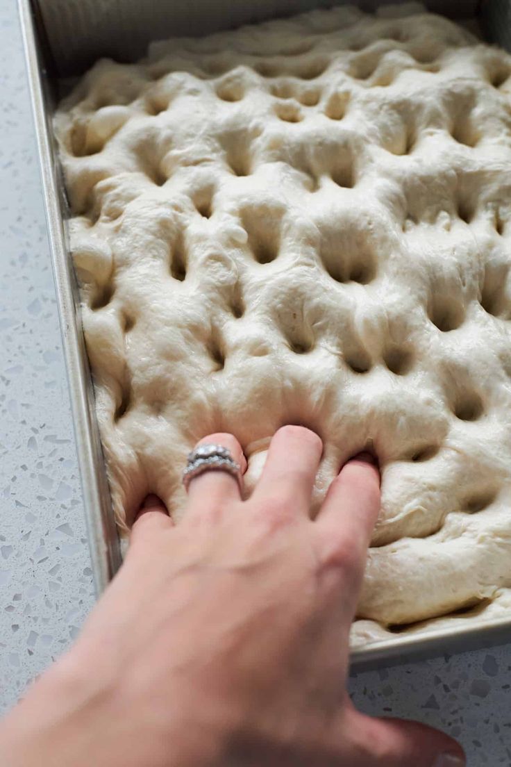 a person placing dough into a pan with their hand on the top and fingers pointing at it