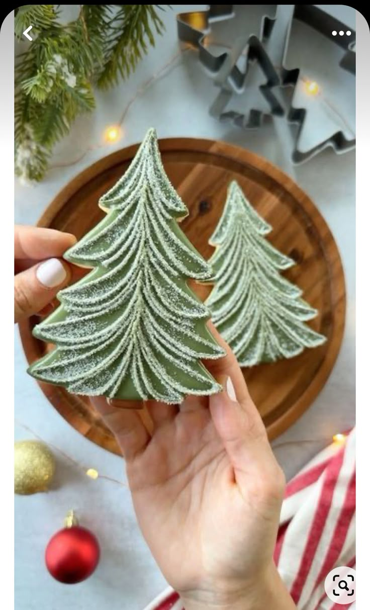 someone is holding up a small christmas tree cookie