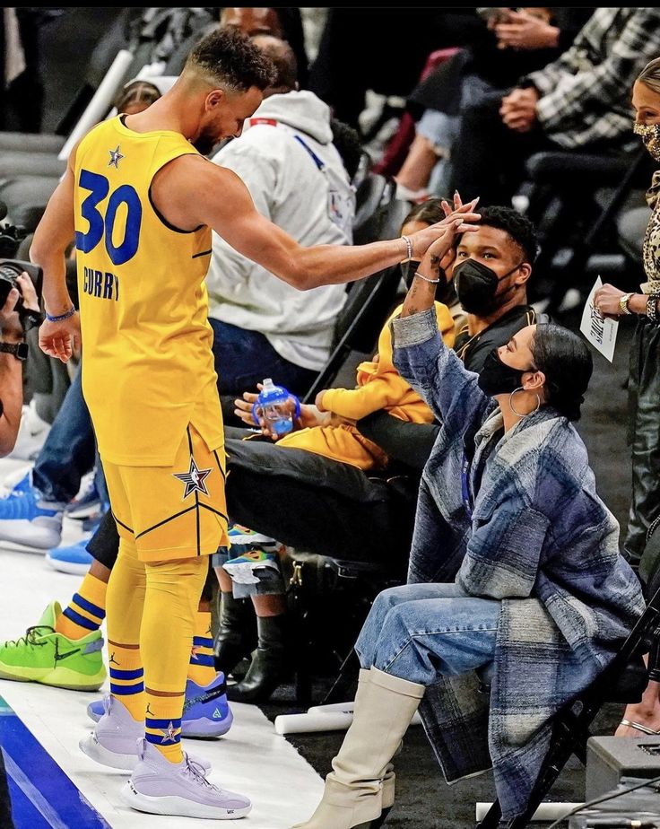 the basketball player is getting his hair combed by an older man in a yellow uniform