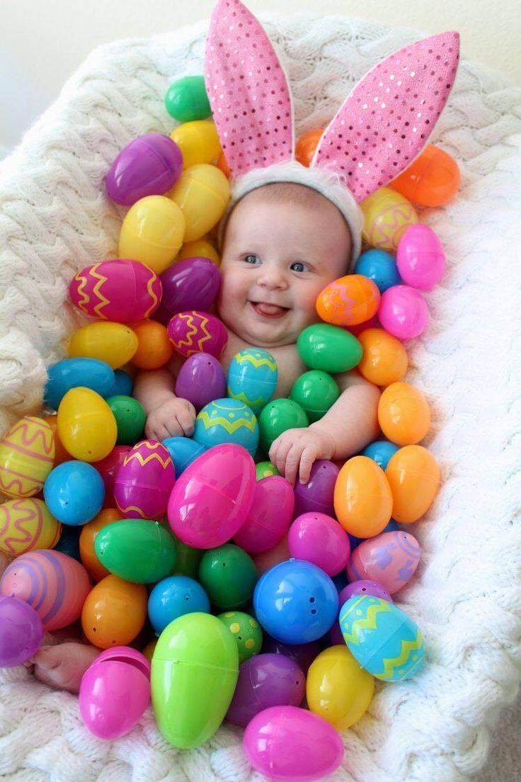 a baby sitting in a basket filled with easter eggs