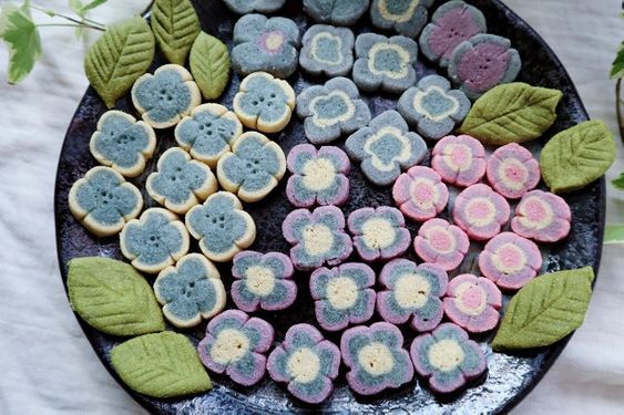 some cookies are on a plate with leaves and flowers in the shape of flower petals