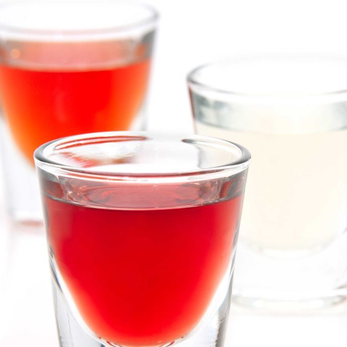 three glasses filled with liquid sitting on top of a white table next to each other