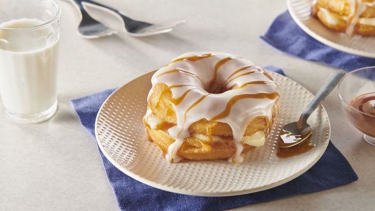 a plate with a donut covered in icing on it next to a glass of milk