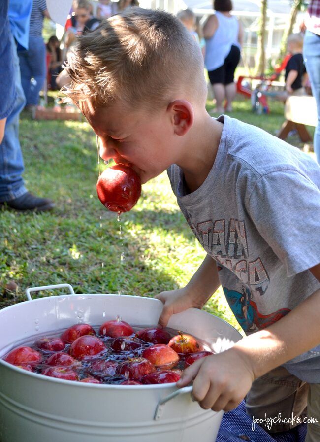 a young boy picking up some fruit from a bucket