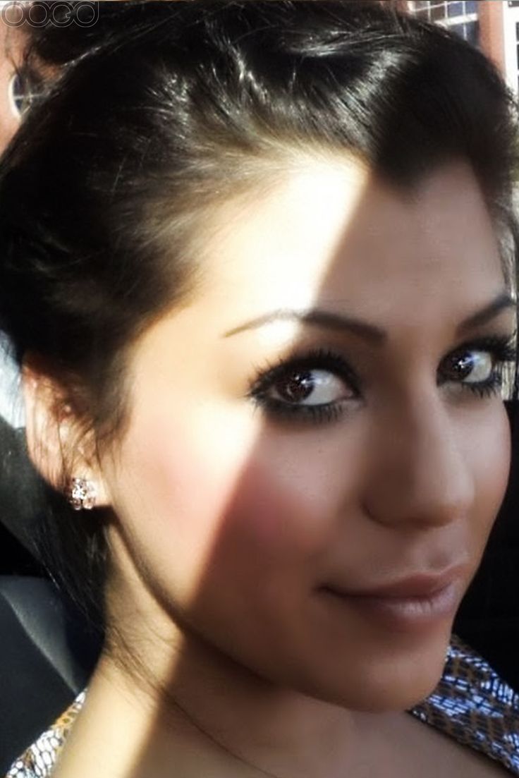 a close up of a woman with dark hair and blue eyeshadow, in a car