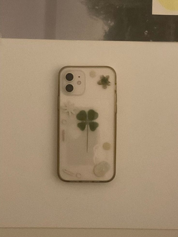 an iphone case with four leaf clovers attached to the side of a white wall