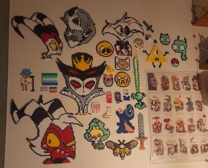 an assortment of pixel art is displayed on a white wall next to pictures and stickers