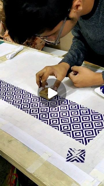 a man working on an art project with blue and white fabric in front of him