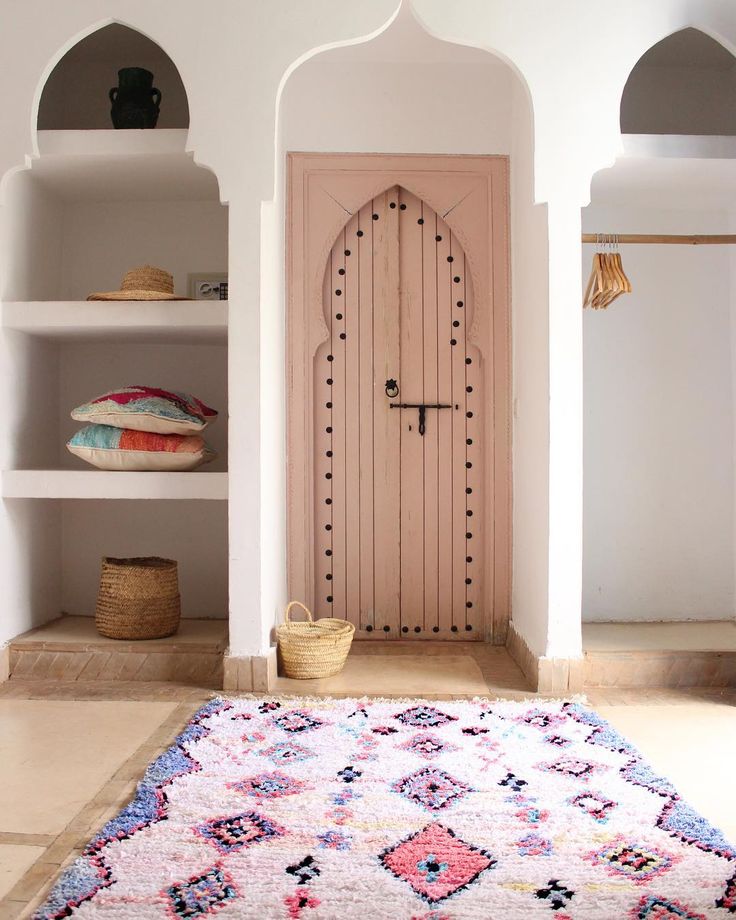 a room with a rug, shelves and a door