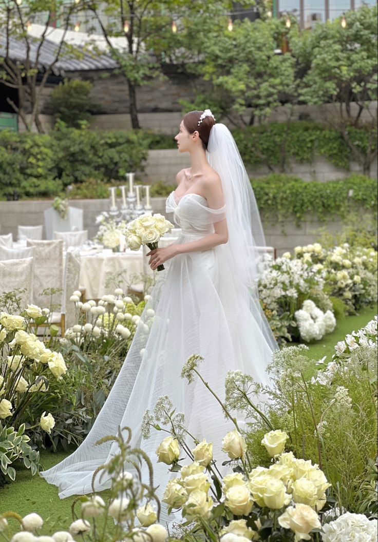 a woman in a white wedding dress standing next to flowers