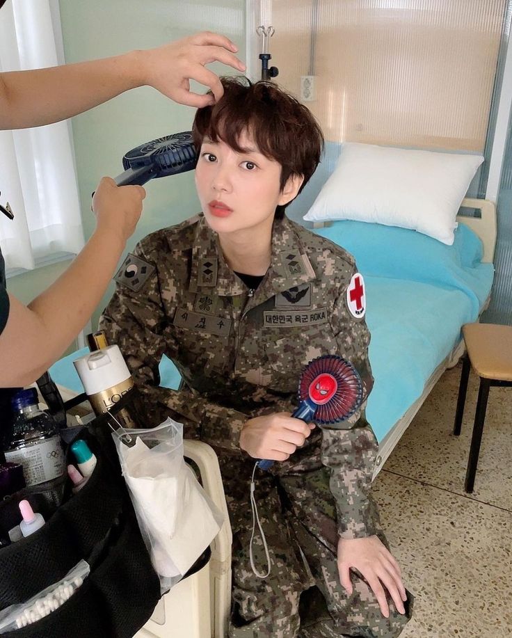 a woman is getting her hair done at the same time as an army man in uniform