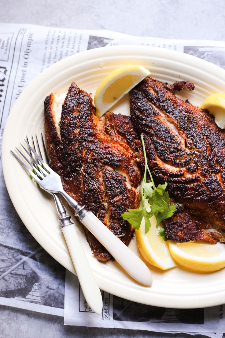 two pieces of meat on a plate with lemons and parsley