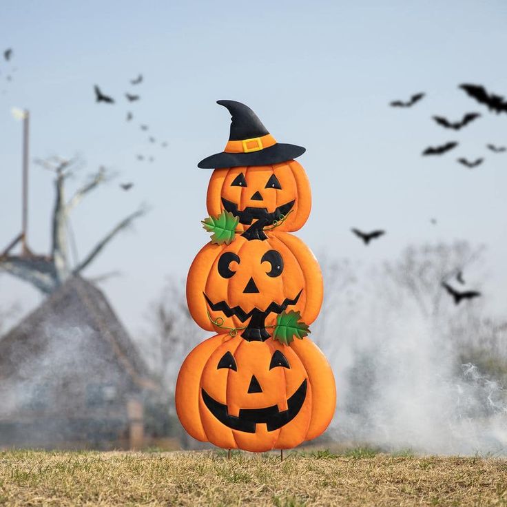 three pumpkins stacked on top of each other with bats flying in the sky behind them