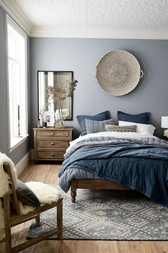 a bed room with a neatly made bed and a chair in front of a window