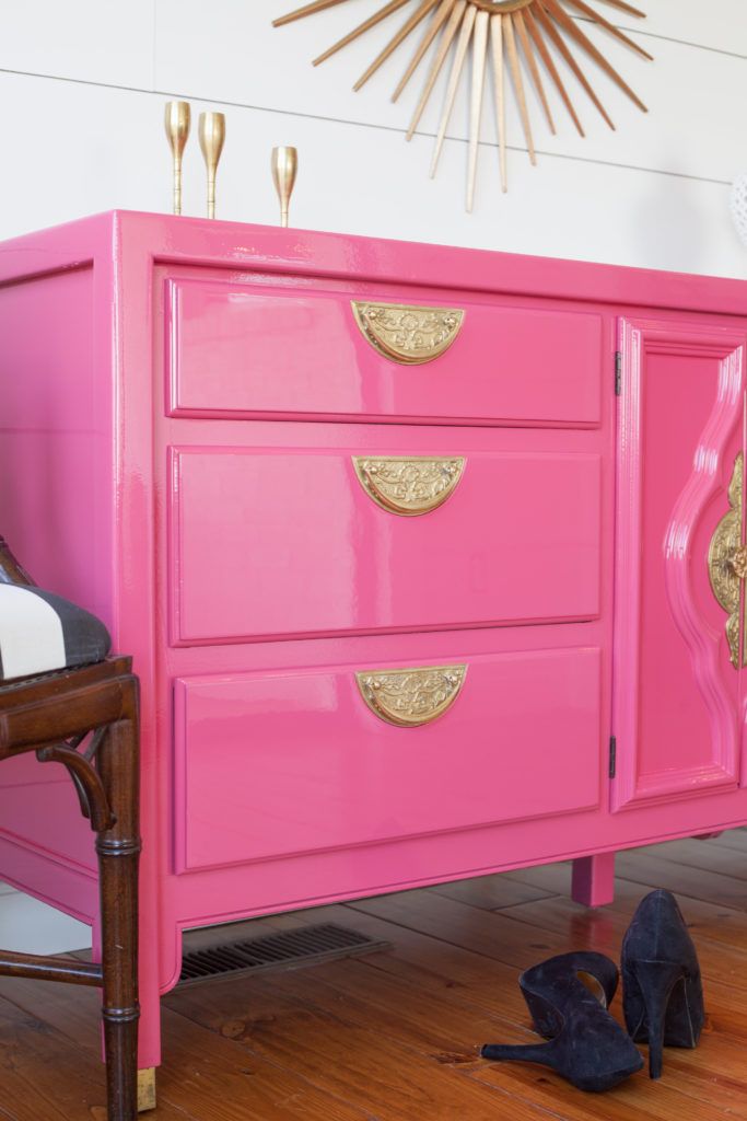 a pink dresser with gold handles in a room