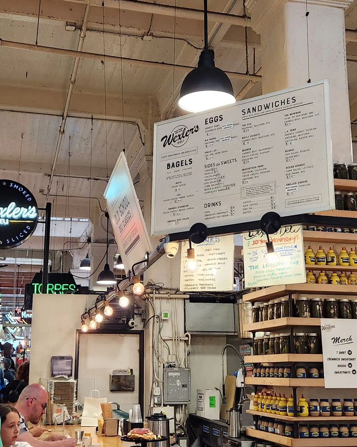 the inside of a restaurant with menus hanging from the ceiling and people sitting at tables