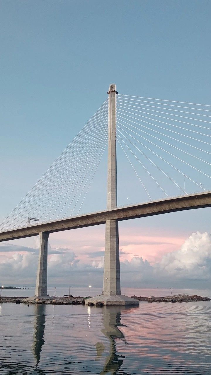 a bridge that is over water with clouds in the background