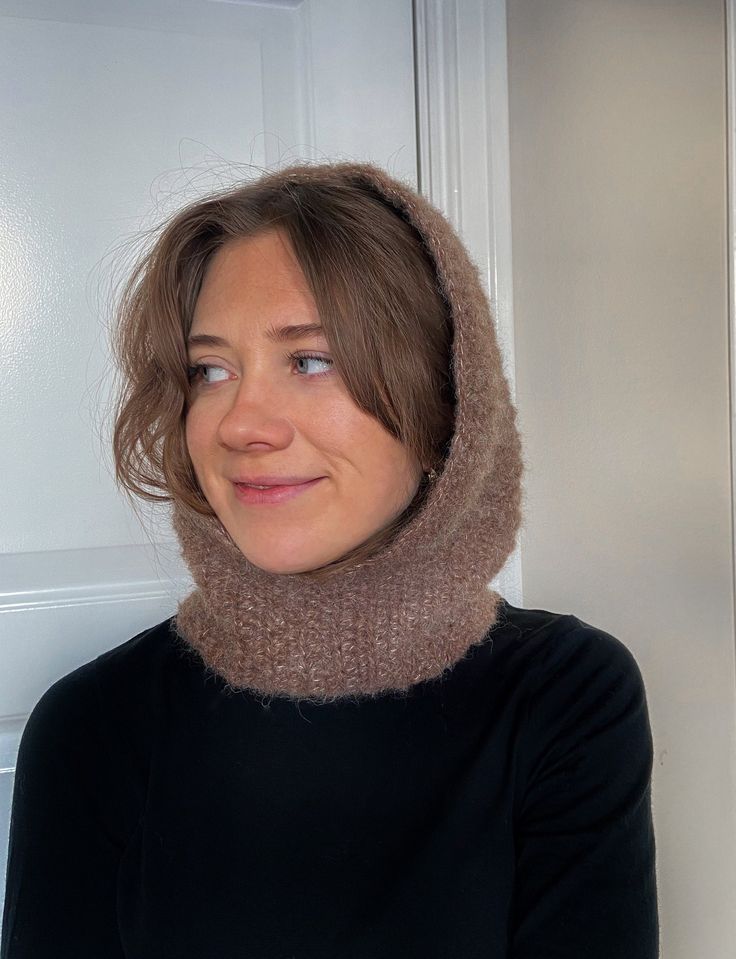 a woman wearing a cowgirl neck scarf in front of a white door with a cat on it