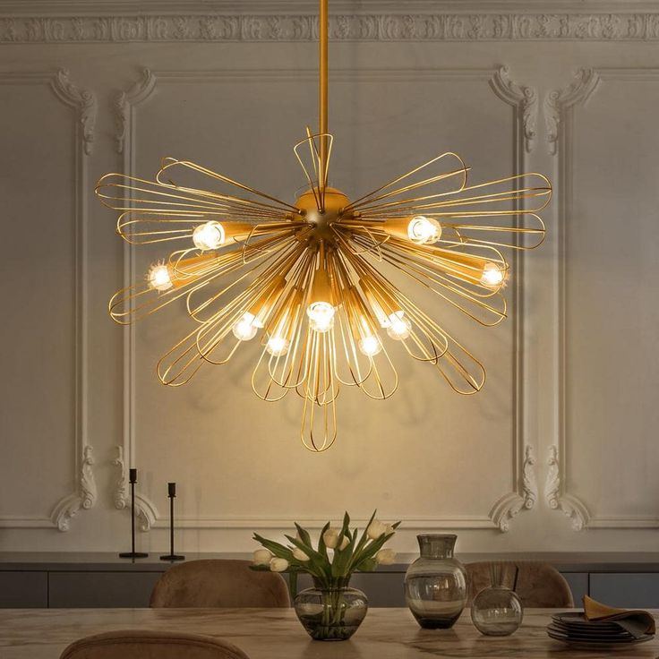 a chandelier hanging over a dining room table with chairs and vases on it