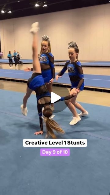 two girls in blue and black cheerleaders doing tricks on the floor with their hands together