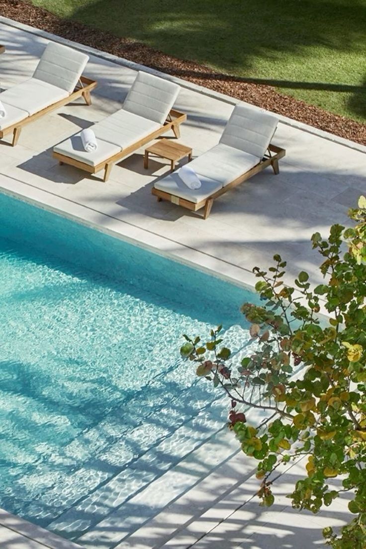 an empty swimming pool with lounge chairs and trees in the foreground, overhead view