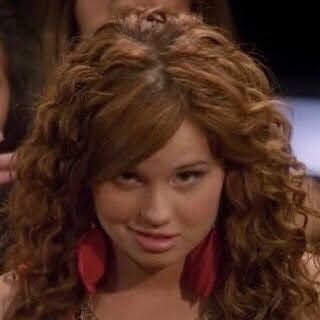 a close up of a person with curly hair and a red scarf around her neck