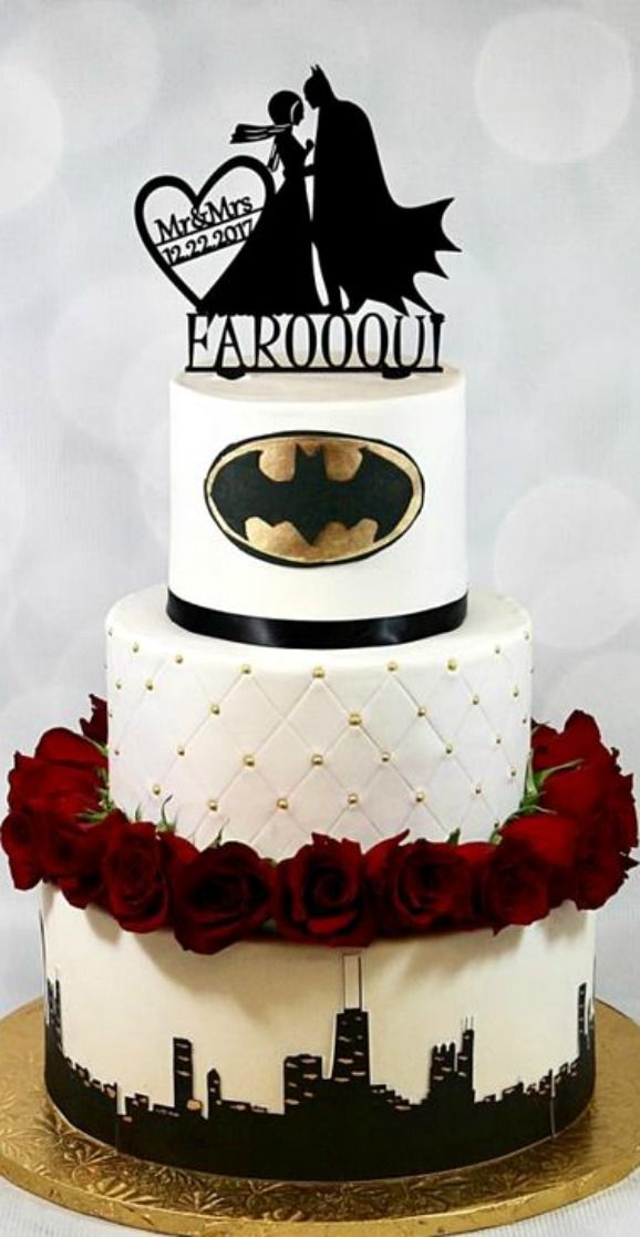 a three tiered wedding cake decorated with red roses and batman silhouettes on top