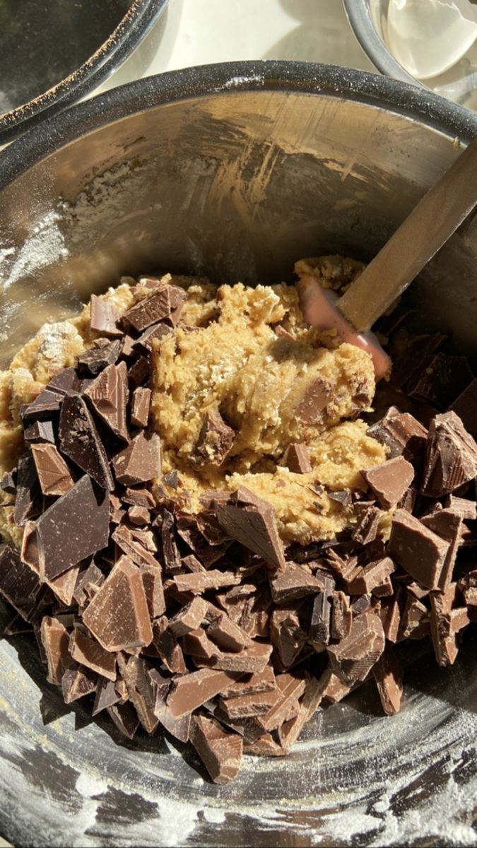 a bowl filled with chocolate chunks next to a metal container full of other food items