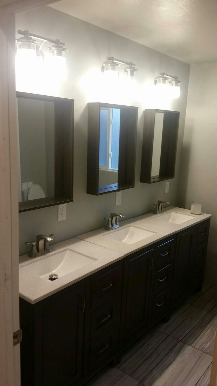 a bathroom with double sinks, mirrors and two lights on the side of the wall