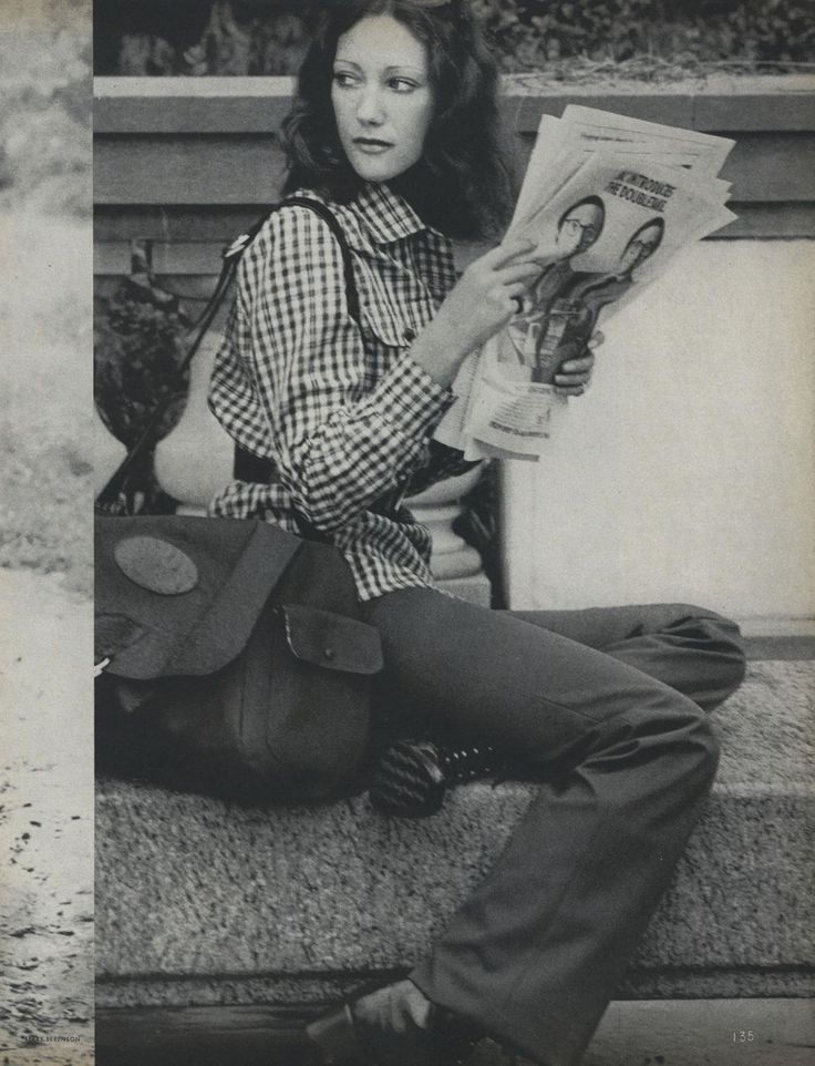 a woman sitting on the ground reading a magazine