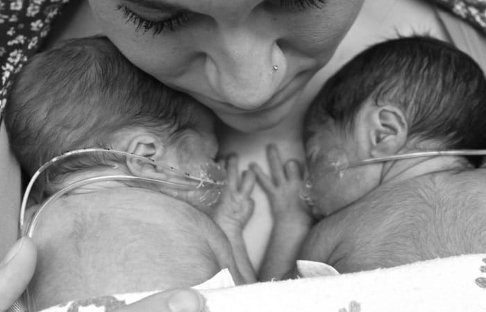 a woman holding two babies in her arms