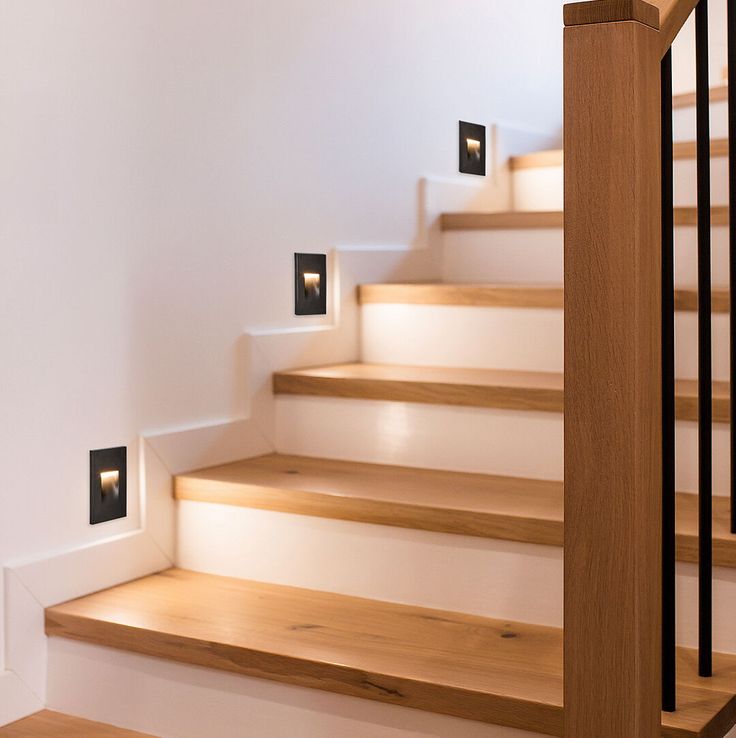 there are some lights on the stairs in this house that is white and wood with black trim