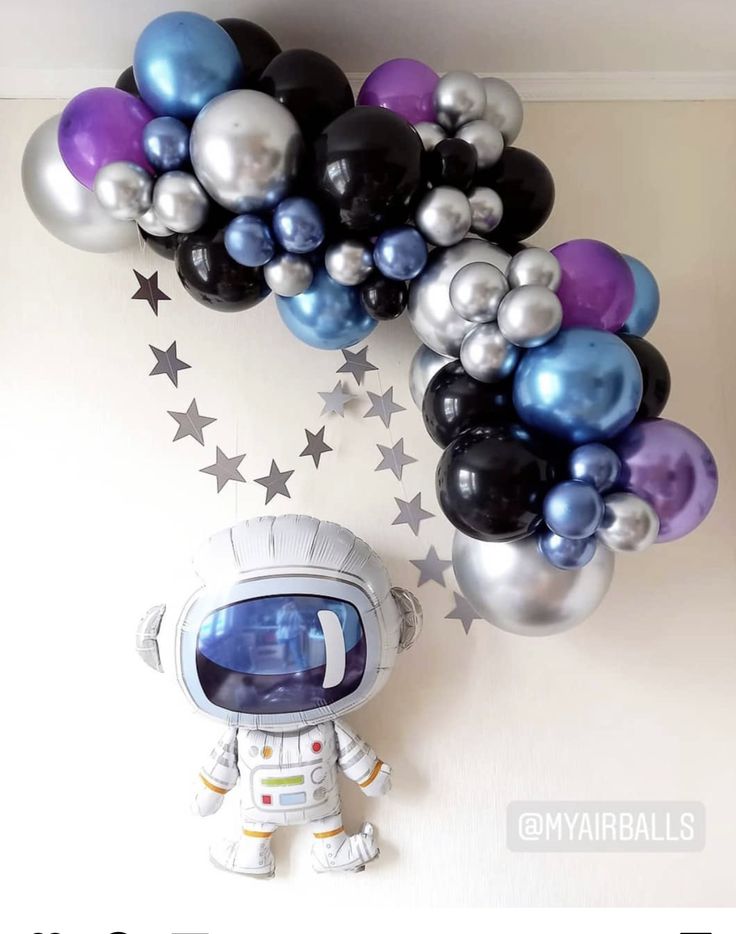 an astronaut balloon wall hanging from the ceiling with stars and balloons attached to it's sides