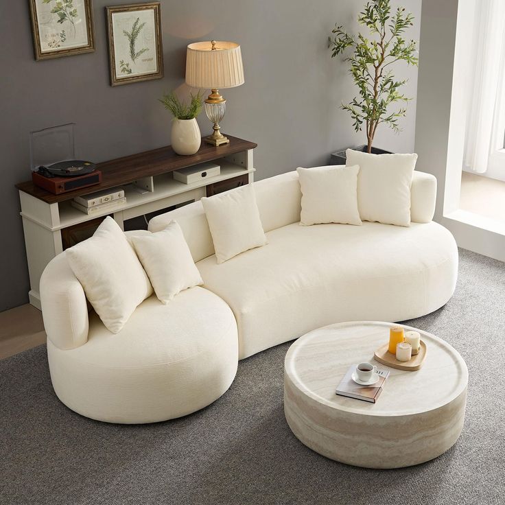 a living room with a large white couch and coffee table on the carpeted floor