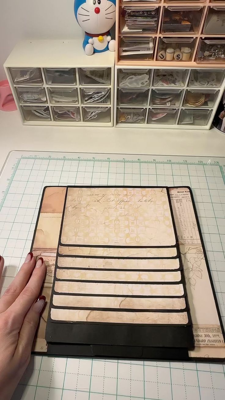 a person is cutting wood with scissors on a table next to some shelves and drawers