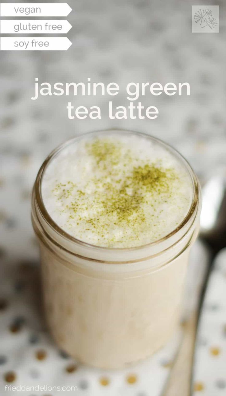 a jar filled with green tea latte sitting on top of a table next to a spoon