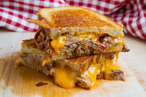 a grilled cheese sandwich on a cutting board with a red and white checkered napkin