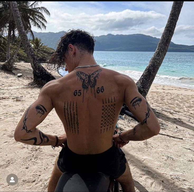 a man riding on the back of a brown horse down a beach covered in palm trees