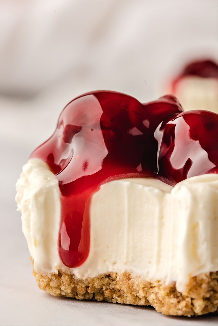 a piece of cake with cream and cherries on it sitting on a white surface