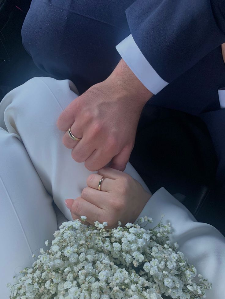 a man and woman holding each other's hands while they sit in a car