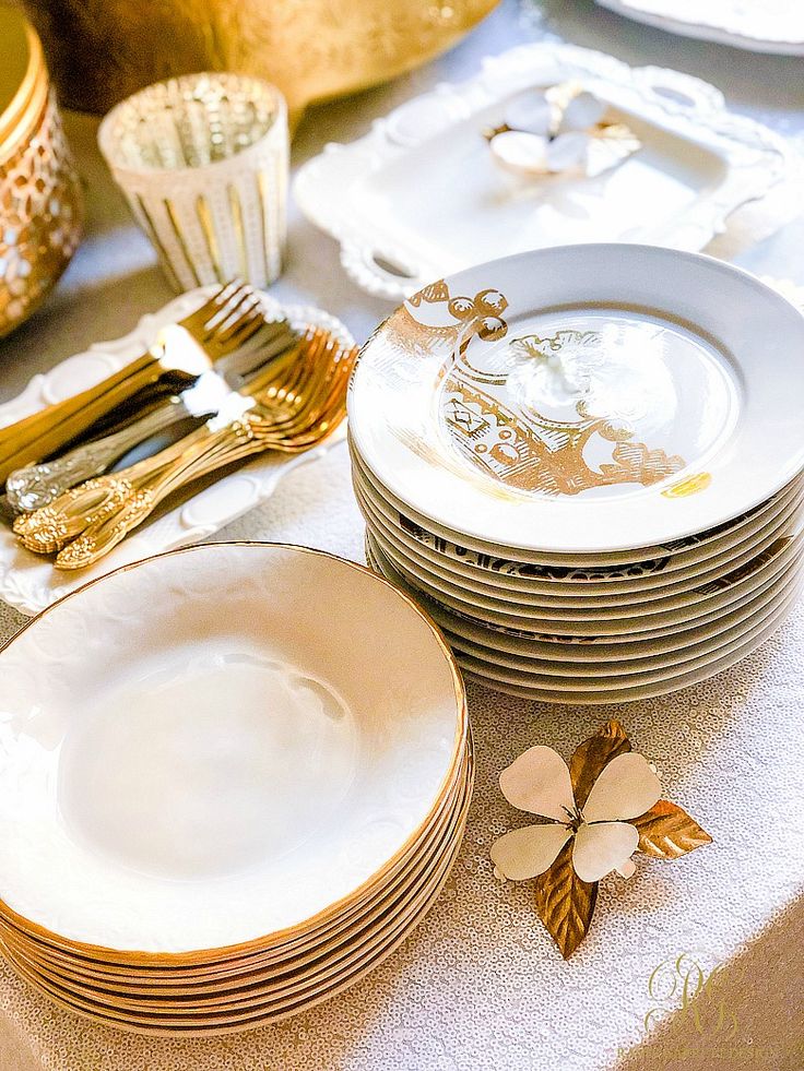 a table topped with lots of white and gold plates