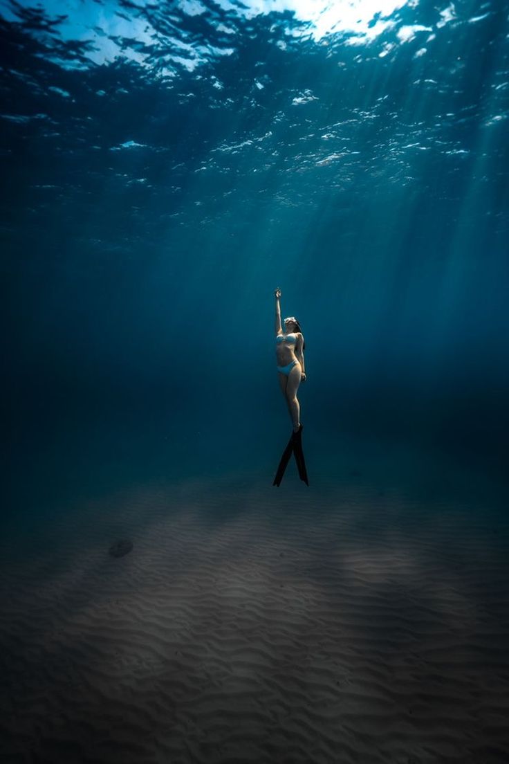 a woman is standing in the water with her arms up